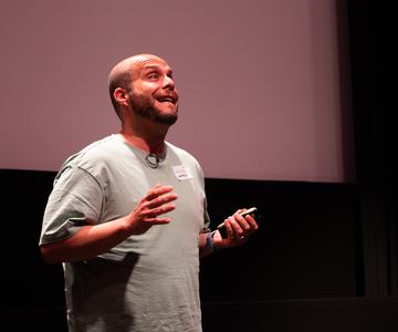 Mario Ferrer mid-gesture on stage at Lead With Tempo